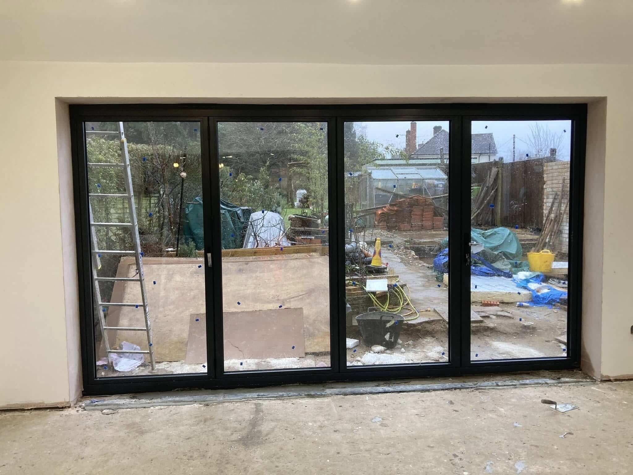 Newly fitted four-panel anthracite bifold doors viewed from inside an extension