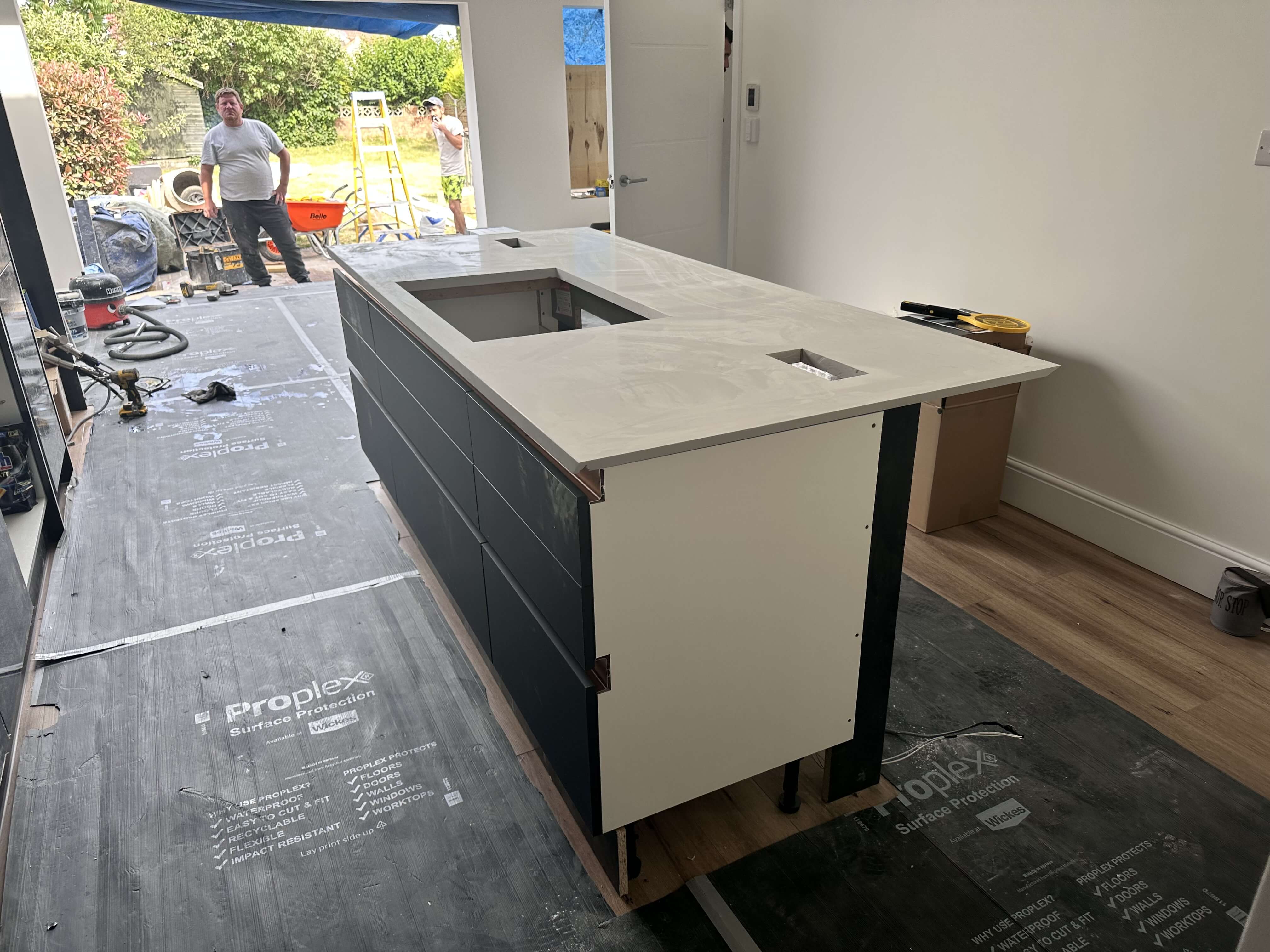 Quartz worktop being lowered onto a navy kitchen island during installation